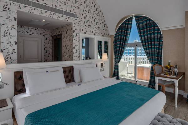 Hotelzimmer im Rubi Platinum Spa Resort & Suites mit einem großen Bett, einem Spiegel und einem Ausblick auf einen Balkon mit einem Whirlpool.
