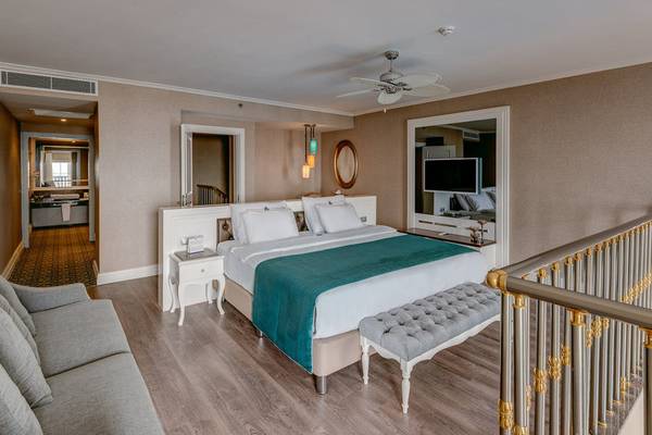 Schlafzimmer im Rubi Platinum Spa Resort & Suites mit Bett, Sofa, Nachttisch und Treppe.