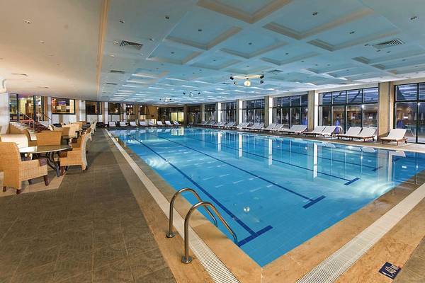 Innenpool des Delphin Deluxe Hotels mit Loungebereich und Sonnenliegen