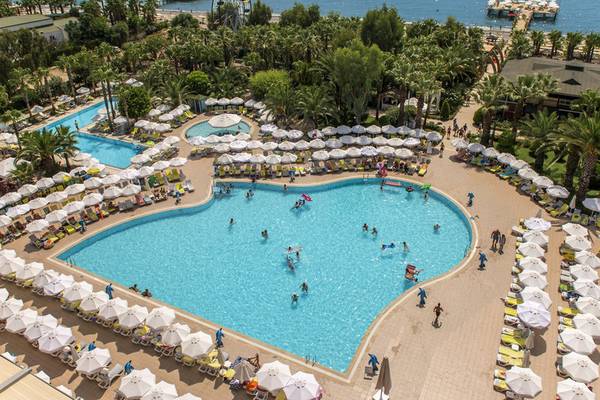 Luftaufnahme des Delphin Deluxe Hotels mit großem Swimmingpool und vielen Sonnenschirmen.