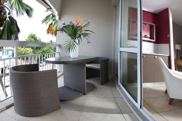 Ein Balkon des La Pagerie - Tropical Garden Hotel mit Tisch, Stühlen und einer Vase mit Blumen.