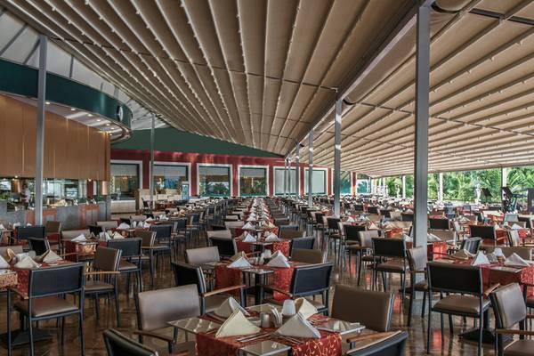 Ein geräumiges Restaurant im Delphin Deluxe Hotel mit vielen gedeckten Tischen und Stühlen.