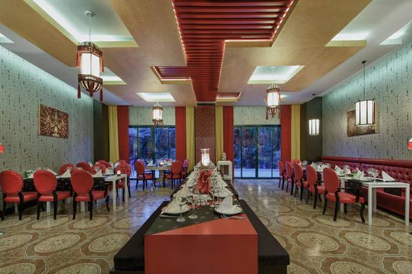 Das elegante Restaurant des Delphin Deluxe Hotels mit roten Stühlen und Tischen, beleuchteten Decken und hängenden Laternen.