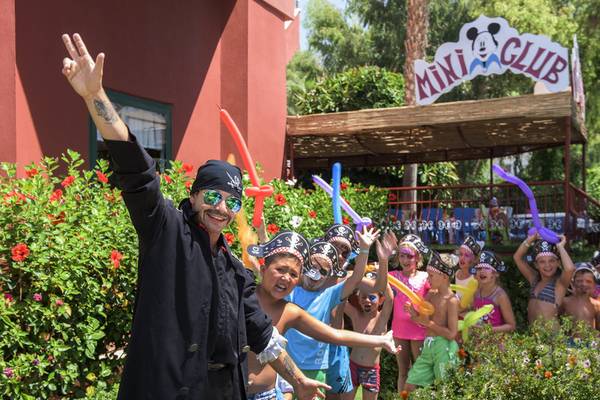 Gruppe von Kindern und einem Mann in Piratenkostümen vor dem Delphin Deluxe Hotel.