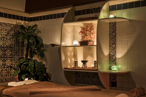 Spa Behandlungsraum im Delphin Deluxe Hotel mit Massageliege, Pflanzen und dekorativen Elementen.