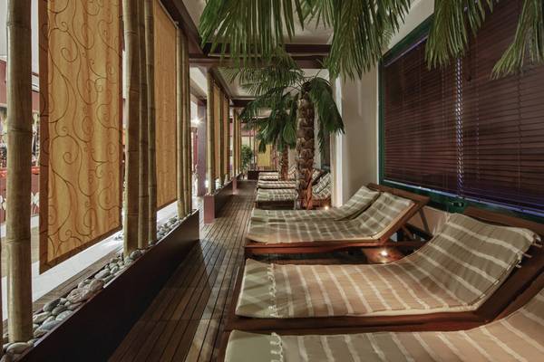 Loungebereich im Delphin Deluxe Hotel mit Holzliegen und Palmen