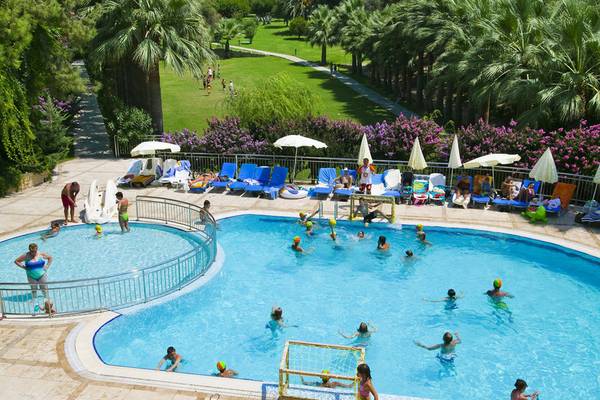 Mehrere Schwimmbecken im Melas Holiday Village mit vielen Kindern, die spielen und einige Erwachsene, die sich entspannen.