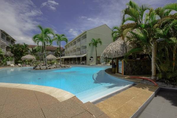 Außenpool des La Pagerie - Tropical Garden Hotel mit Palmen und Sonnenschirmen.