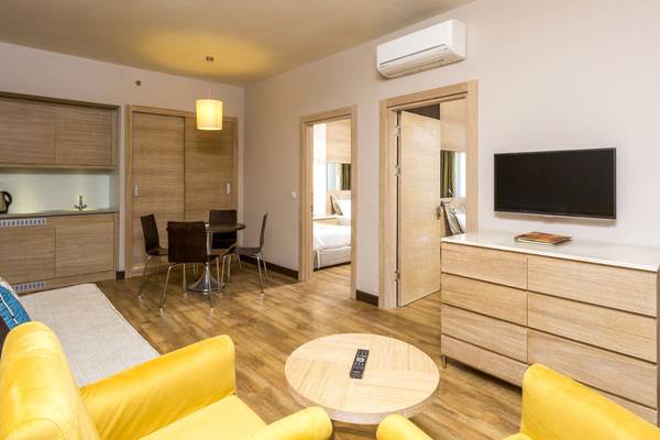 Innenansicht einer Suite im Melas Holiday Village mit Wohnzimmer, Schlafbereich und Küche.