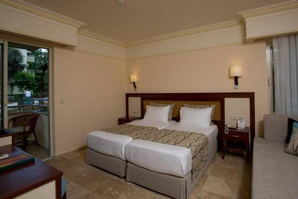 Doppelbett Zimmer im Melas Holiday Village mit Balkon und bequemem Sofa.