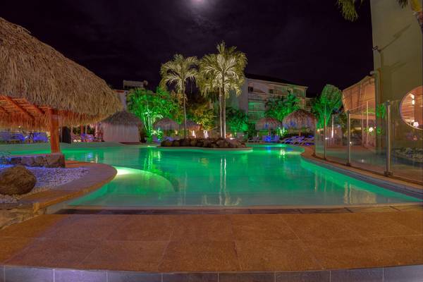 Pool im La Pagerie - Tropical Garden Hotel bei Nacht mit grünen Lichtern und Palmen.