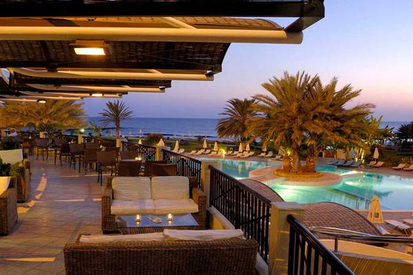 Terrasse des Constantinou Bros Athena Beach Hotels mit Blick auf den Pool und das Meer.