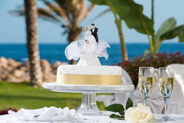 Hochzeitstorte mit Brautpaar-Figuren auf einem Tisch am Strand mit Meerblick