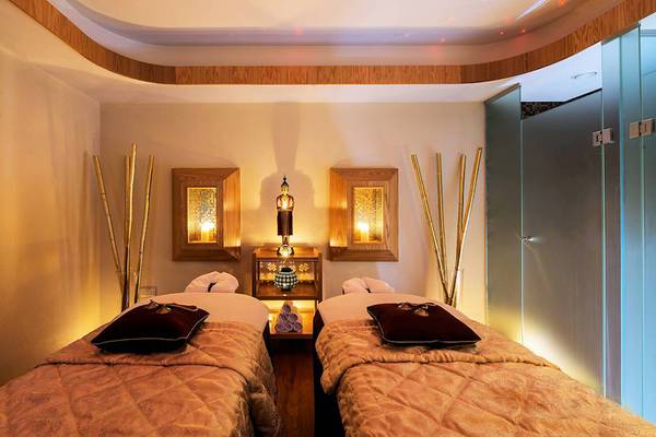 Massagebereich im Constantinou Bros Athena Beach Hotel mit zwei Betten, goldenen Dekorationen und warmem Licht.