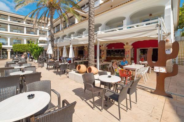 Terrasse des Beach Club Font de Sa Cala Hotels mit Tischen, Stühlen und Palmen