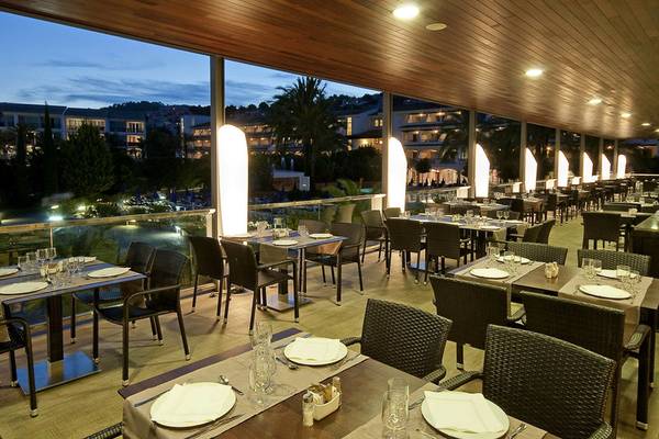 Innenansicht des Restaurants des Beach Club Font de Sa Cala mit Tischen und Stühlen, die mit Tellern, Gläsern und Besteck gedeckt sind.