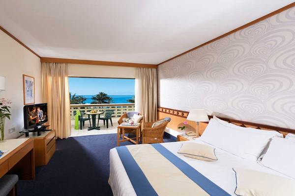Hotelzimmer im Constantinou Bros Athena Beach mit Meerblick, Balkon und Wohnzimmermöbeln.