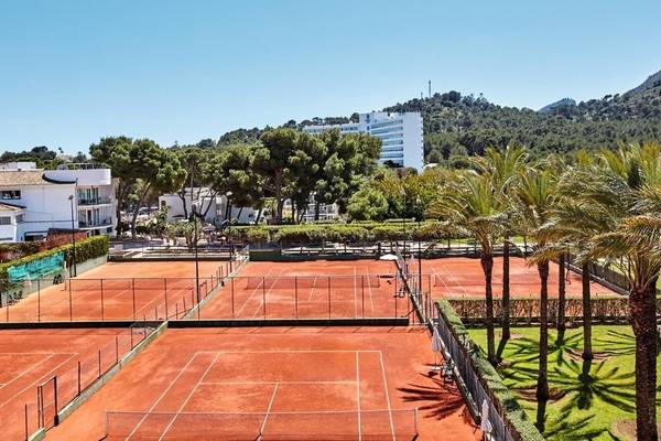 Tennisplatz im Beach Club Font de Sa Cala mit Gebäuden im Hintergrund und Palmen.