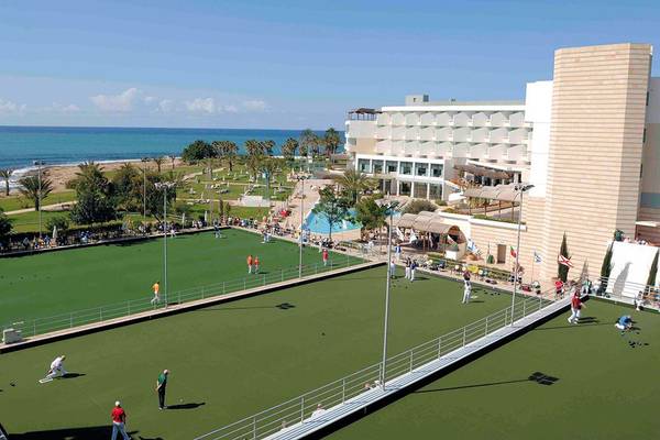Luftaufnahme des Constantinou Bros Athena Beach Hotels mit einem Golfplatz und einer Küste im Hintergrund.