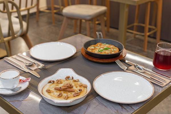 Ein Tisch im Hellenic Vibes Smart Hotel in Athen, gedeckt mit Geschirr, Gerichten und Getränken.