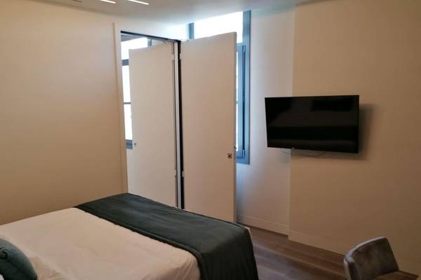 Schlafzimmer im Hellenic Vibes Smart Hotel in Athen mit einem Bett, Fernseher an der Wand und einem Stuhl.