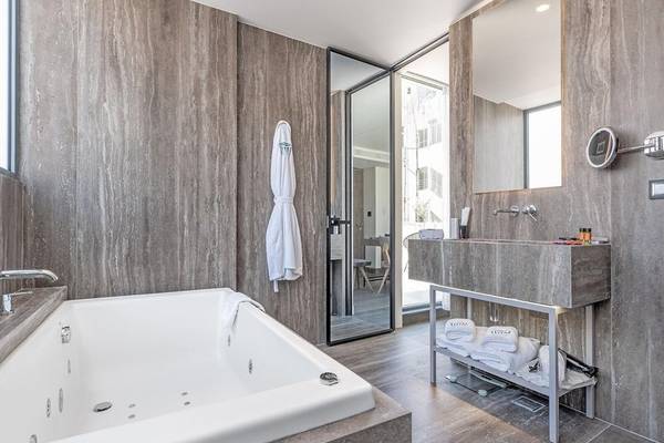 Badezimmer im Hellenic Vibes Smart Hotel in Athen mit Badewanne, Waschbecken und Marmorwänden.