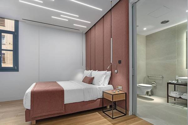 Innenansicht eines Schlafzimmers im Hellenic Vibes Smart Hotel in Athen mit Bett, Nachttisch und Fenster.