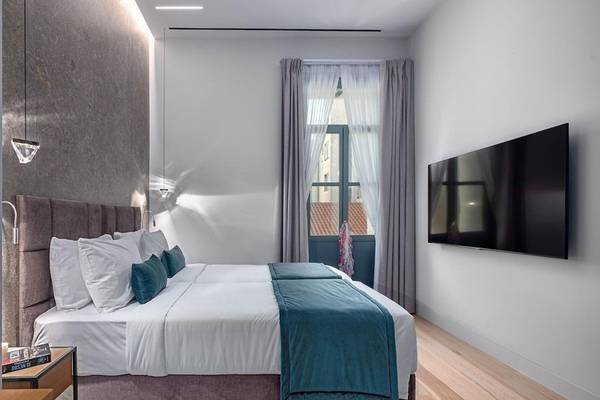 Schlafzimmer im Hellenic Vibes Smart Hotel Athens mit Doppelbett, Fernseher und Fenster mit Vorhängen.