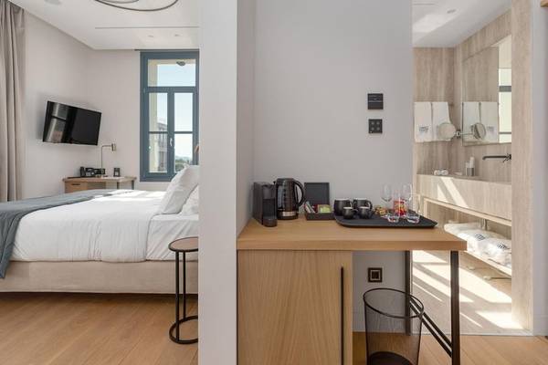 Innenansicht eines Zimmers im Hellenic Vibes Smart Hotel Athens mit Bett, Fernseher und Schreibtisch.