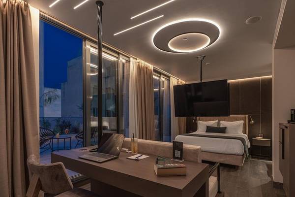 Schlafzimmer im Hellenic Vibes Smart Hotel in Athen mit Laptop, Schreibtisch, Bett, und großer Fensterfront.