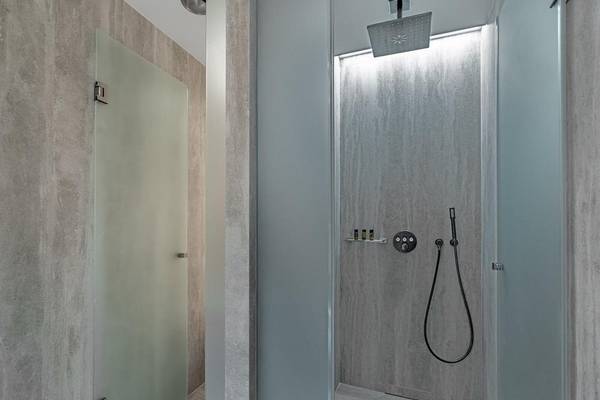 Dusche im Hellenic Vibes Smart Hotel in Athen mit grauen Wänden und Boden.