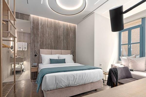 Schlafzimmer im Hellenic Vibes Smart Hotel in Athen mit Bett, Holzboden und modernem Interieur.