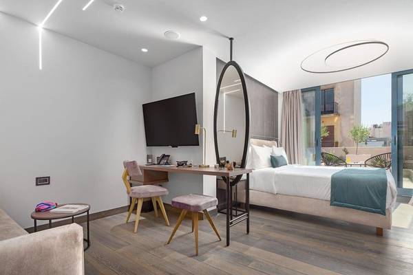 Innenansicht eines Zimmers im Hellenic Vibes Smart Hotel Athens mit Bett, Schreibtisch und Fernseher.