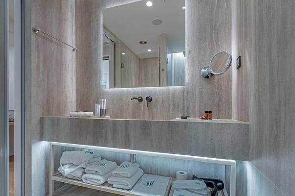 Hellenic Vibes Smart Hotel Athens Badezimmer mit Waschbecken, Spiegel und Handtüchern.