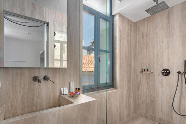 Innenansicht eines Badezimmers im Hellenic Vibes Smart Hotel Athens mit Dusche, Waschbecken und Spiegel.