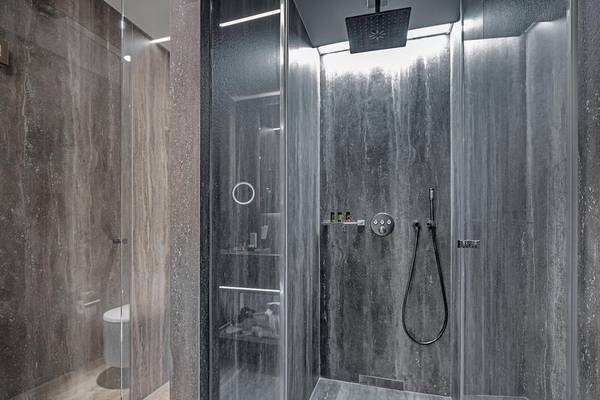 Ein modernes Badezimmer mit einer Glasdusche und grauen Wänden im Hellenic Vibes Smart Hotel in Athen.