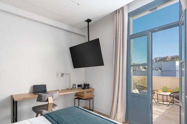Ein modernes Zimmer im Hellenic Vibes Smart Hotel in Athen mit Schreibtisch, Laptop, Fernseher und Balkon.