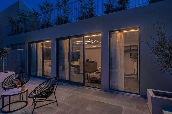 Hellenic Vibes Smart Hotel in Athen, Außenbereich bei Nacht mit Terrasse, Möbeln und Pflanzen.