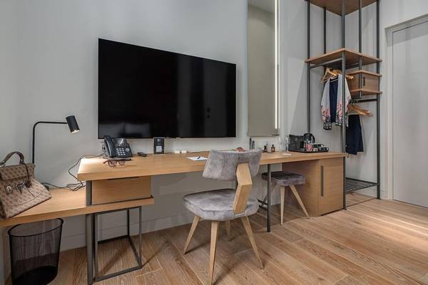 Innenansicht eines Zimmers im Hellenic Vibes Smart Hotel in Athen mit Schreibtisch, Fernseher und Kleiderständer.