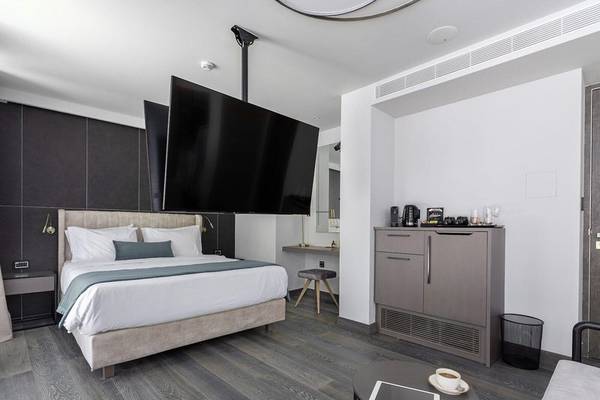 Schlafzimmer im Hellenic Vibes Smart Hotel in Athen mit Bett, Fernseher und Tisch