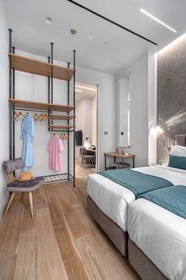 Hellenic Vibes Smart Hotel Zimmer mit zwei Betten, Kleiderständer und Schreibtisch
