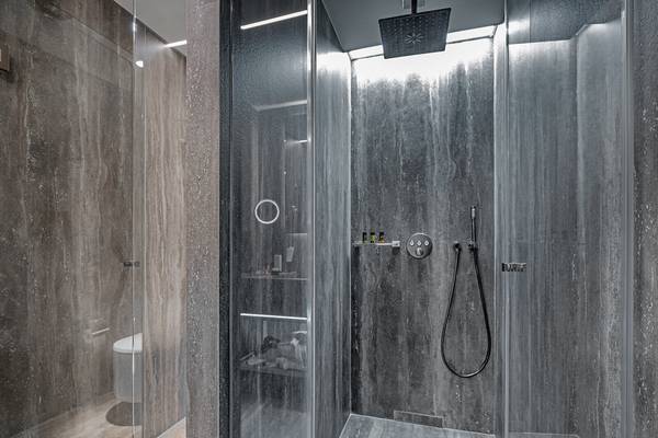 Dusche im Hellenic Vibes Smart Hotel in Athen mit grauen Marmorwänden und Glas.
