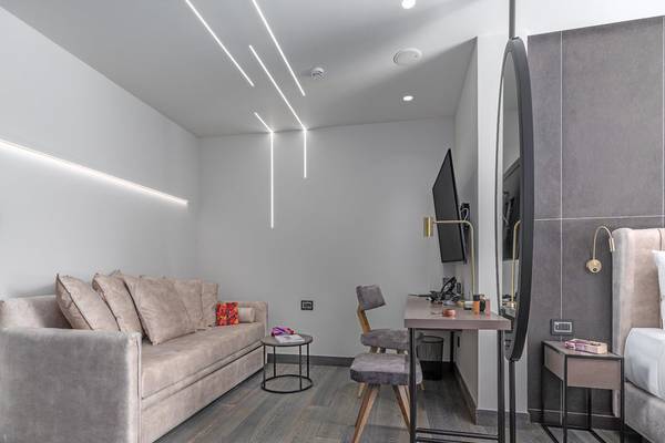 Innenansicht eines Zimmers im Hellenic Vibes Smart Hotel in Athen mit Couch, Schreibtisch und Fernseher.