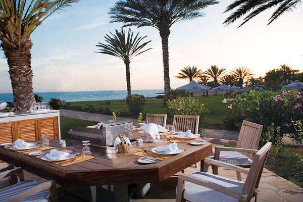 Außenterrasse des Constantinou Bros Athena Beach Hotels mit Grill und Blick auf den Ozean