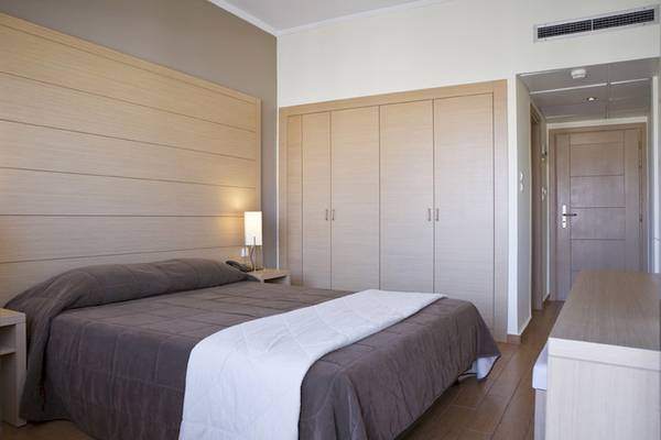 Schlafzimmer im Parnon Hotel mit Doppelbett, Nachttischen und Einbauschränken.