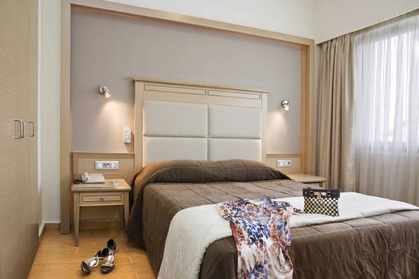 Schlafzimmer im Parnon Hotel mit Doppelbett, Nachttischen und Kleidern.
