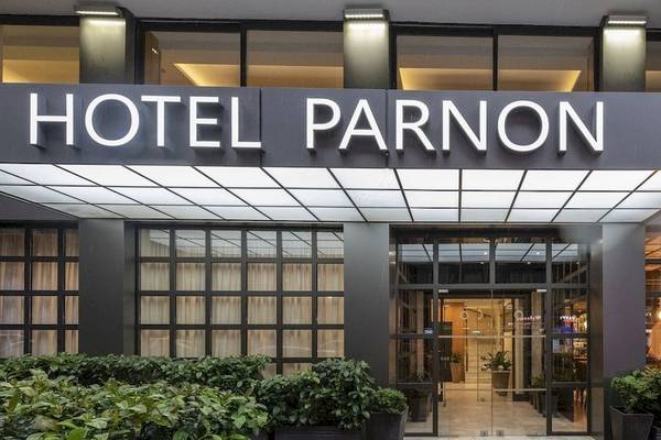 Hotel Parnon Eingang mit Glasfront und Bepflanzung vor dem Eingang.