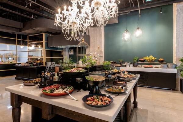 Buffet-Tisch im Skylark, Aluma Hotel & Resort mit verschiedenen Gerichten, Pflanzen und einer Kristallkronleuchter.