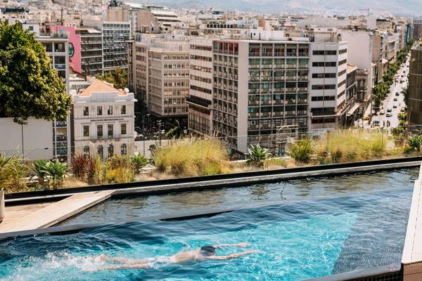 Aussicht auf den Dachpool des Skylark Aluma Hotel & Resort mit einem Schwimmer im Hintergrund der Stadt