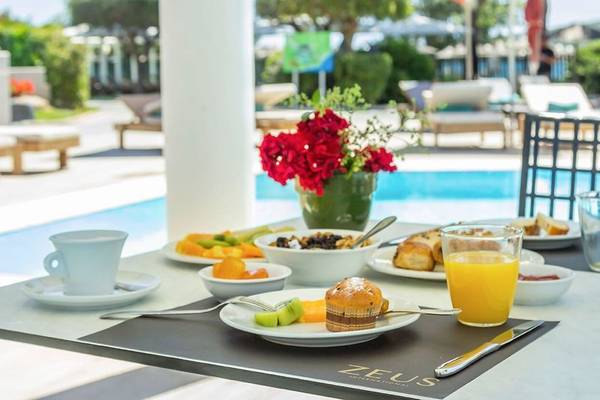 Frühstückstisch im Hotel Dolce Athens Attica Riviera mit Früchten, Brot und Saft.